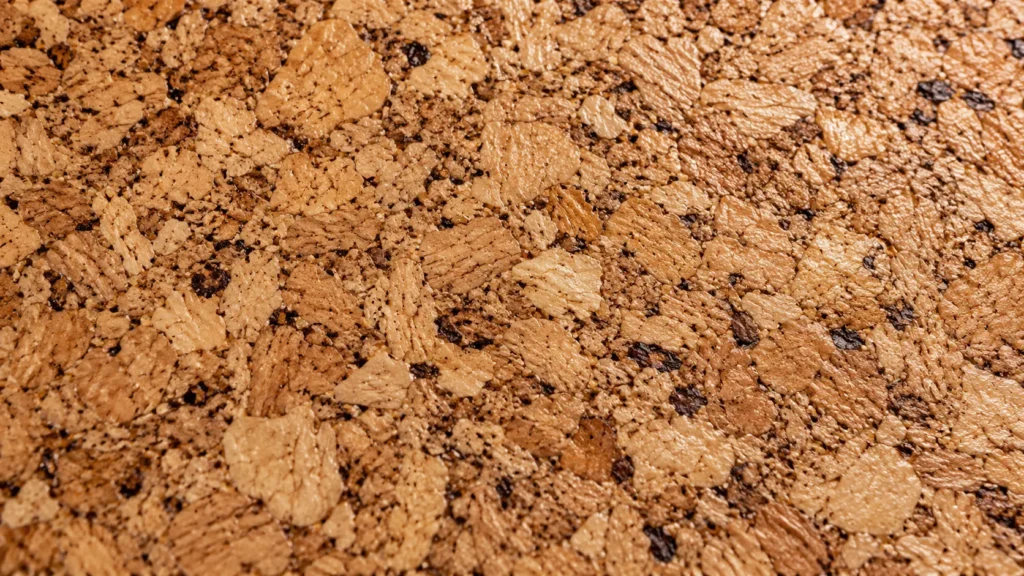 Extreme close-up of agglomerated cork floor tile showing warm tan and caramel cork granules with a subtle satin finish.